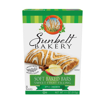 Image of a carton of Sunbelt Bakery's Soft Baked Bars with Sweet Fruit Filling in Apple Cinnamon flavor. The box displays an image of a golden-brown bar drizzled with white icing beside slices of fresh apple and cinnamon sticks. Emphasized are the whole grain content and the package weight of 11 oz (312g) with a green and white color theme